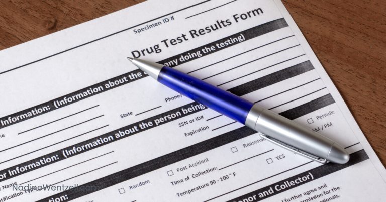 Close-up of a blank drug test results form with a blue and silver pen resting on top. The form includes fields for personal information and checkboxes for testing reasons.